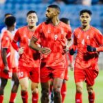 لاعب كرة قدم يرتدي زي أحمر يحمل الرقم 9 يركض في الملعب.