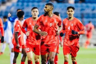لاعب كرة قدم يرتدي زي أحمر يحمل الرقم 9 يركض في الملعب.