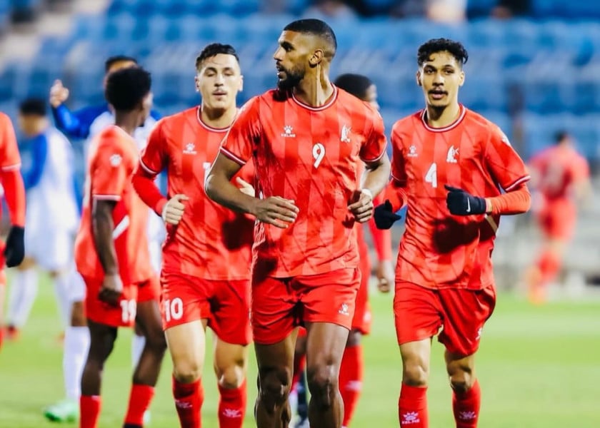 لاعب كرة قدم يرتدي زي أحمر يحمل الرقم 9 يركض في الملعب.