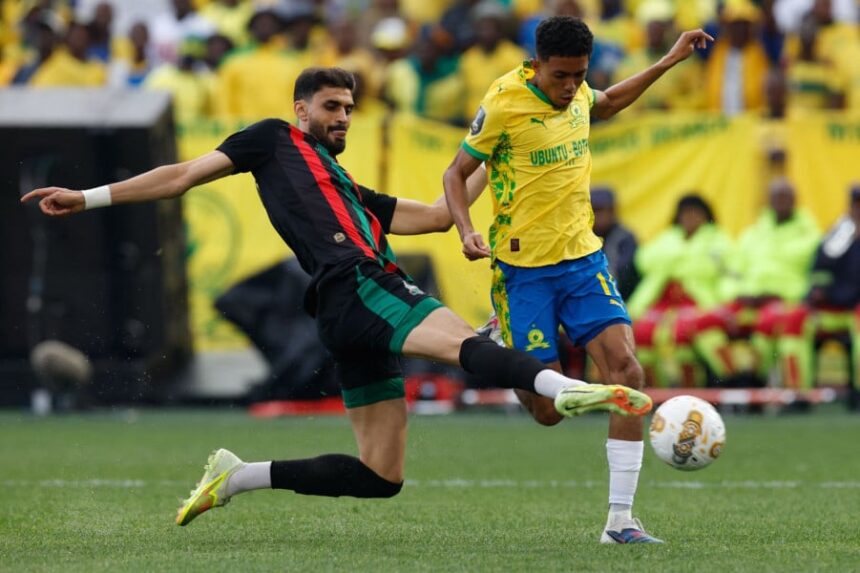 لاعب بالقميص الأصفر والأسود يركل الكرة أمام لاعب بالأسود