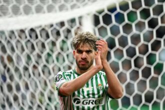 لاعب كرة قدم يرتدي زي GREE يصفق بيديه.