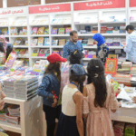 فتيات يشاهدن الكتب على رفوف مكتبة المعرض