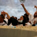 حاجة ترتدي حجابًا وقناعًا تنظر إلى رأسها.