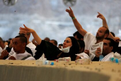 حاجة ترتدي حجابًا وقناعًا تنظر إلى رأسها.