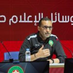 رضوان جيد يتحدث أمام ميكروفون بخلفية حمراء.