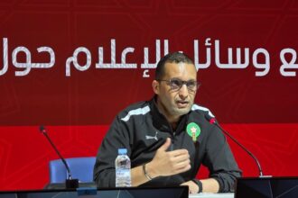 رضوان جيد يتحدث أمام ميكروفون بخلفية حمراء.