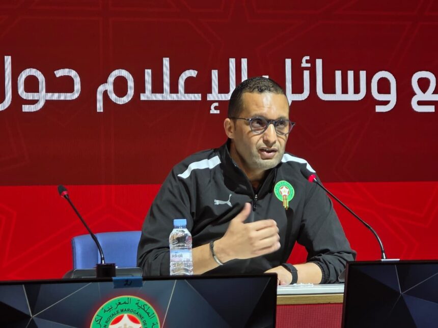 رضوان جيد يتحدث أمام ميكروفون بخلفية حمراء.