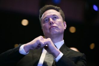 رجل يرتدي بدلة سوداء ويداه أمام وجهه ينظر للأعلى
