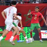 لاعب مغربي يراوغ بالكرة في مباراة كرة قدم.