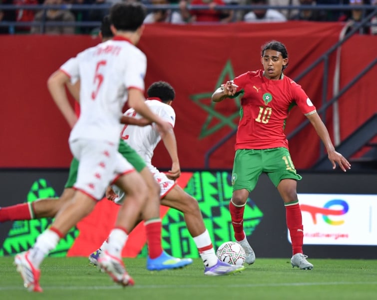 لاعب مغربي يراوغ بالكرة في مباراة كرة قدم.