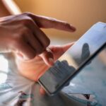 شخص يحمل هاتفًا محمولًا ويتصفح خريطة أو تطبيقًا