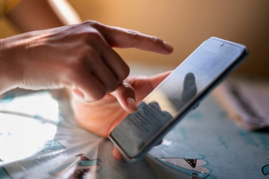 شخص يحمل هاتفًا محمولًا ويتصفح خريطة أو تطبيقًا
