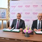 رجلان يبتسمان ويجلسان على طاولة يحملان وثائق
