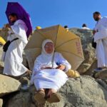 امرأة تجلس تحت مظلة في يوم حار بمكة المكرمة.