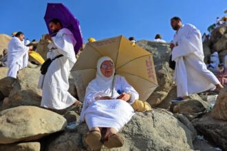 امرأة تجلس تحت مظلة في يوم حار بمكة المكرمة.