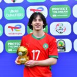 لاعب شاب يحمل كأس البطولة أمام شعاري UNAF و Total Energies