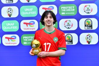 لاعب شاب يحمل كأس البطولة أمام شعاري UNAF و Total Energies