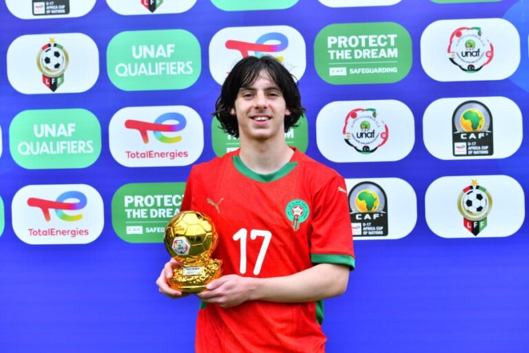 لاعب شاب يحمل كأس البطولة أمام شعاري UNAF و Total Energies