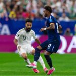 لاعب من الرأس الأخضر يراوغ لاعباً سعودياً في مباراة كرة قدم.