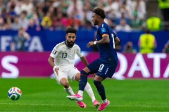 لاعب من الرأس الأخضر يراوغ لاعباً سعودياً في مباراة كرة قدم.