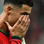 كريستيانو رونالدو يرتدي قميصًا أخضر وأحمر ويضع يديه على وجهه.