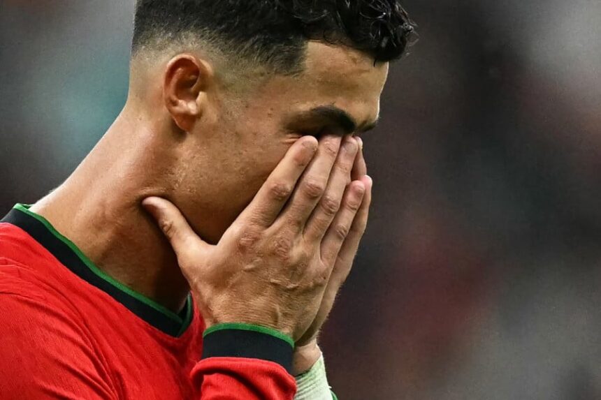 كريستيانو رونالدو يرتدي قميصًا أخضر وأحمر ويضع يديه على وجهه.