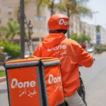 رجل يركب دراجة نارية للتوصيل في شارع بالمدينة.