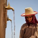 امرأة مسنة عليها تجاعيد تغطي رأسها بكيس من القش.