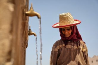 امرأة مسنة عليها تجاعيد تغطي رأسها بكيس من القش.
