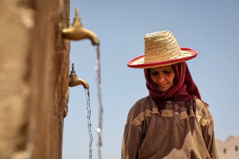امرأة مسنة عليها تجاعيد تغطي رأسها بكيس من القش.