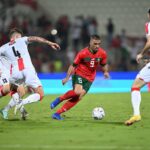 لاعب يحمل الرقم 9 يراوغ لاعبًا آخر بالكرة في مباراة كرة قدم.