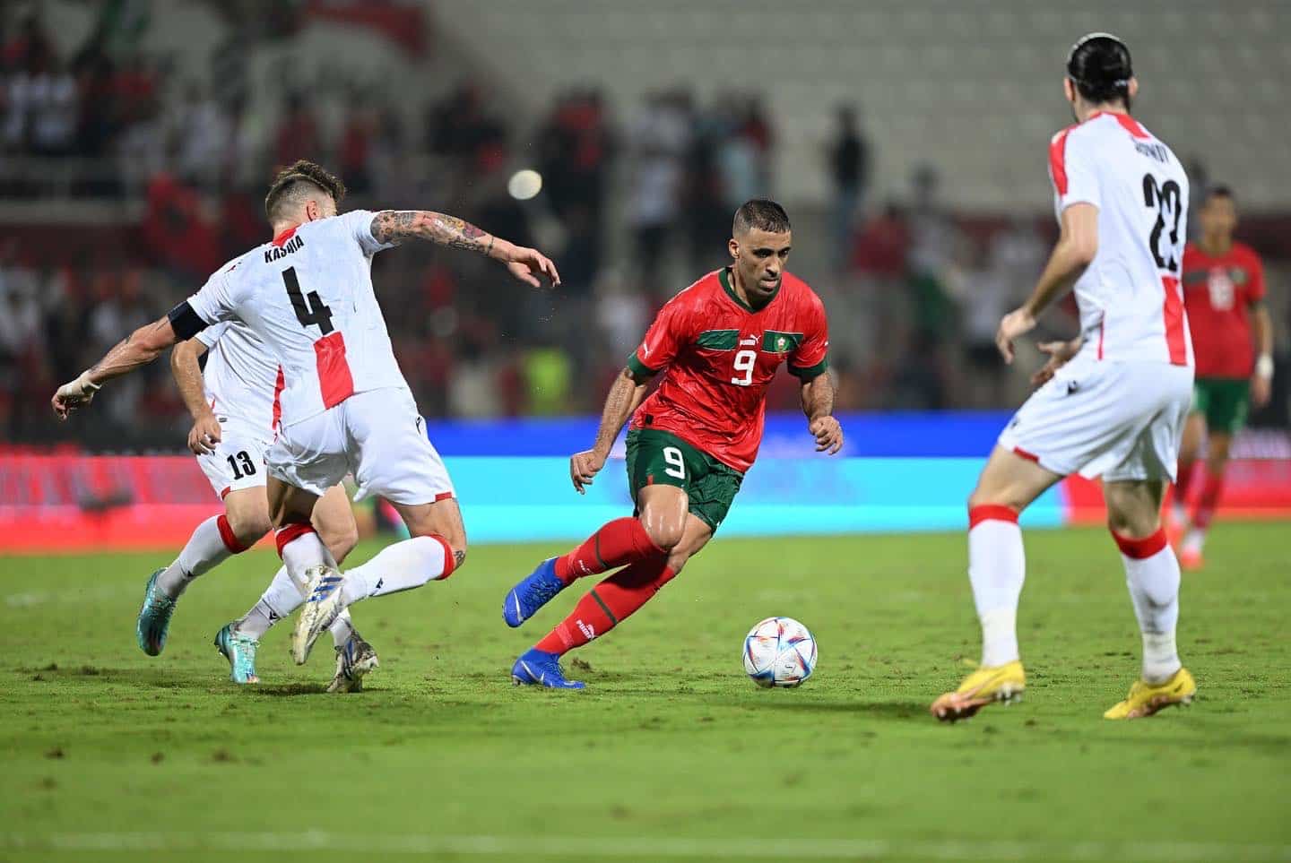 لاعب يحمل الرقم 9 يراوغ لاعبًا آخر بالكرة في مباراة كرة قدم.