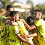 لاعبون يحتفلون بفوز في مباراة كرة قدم بحضور حكم.