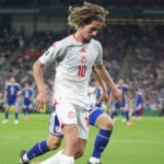 لاعب كرة قدم بالزي الأحمر رقم 10 في الملعب