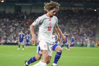 لاعب كرة قدم بالزي الأحمر رقم 10 في الملعب