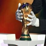 شخص يحمل كأس العالم الذهبي في مكان مظلم.