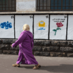 امرأة ترتدي عباءة التخرج البنفسجية بجانب بناء.