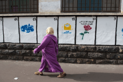 امرأة ترتدي عباءة التخرج البنفسجية بجانب بناء.