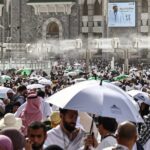 حجاج يتجمعون تحت مظلة كبيرة في يوم حار