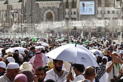 حجاج يتجمعون تحت مظلة كبيرة في يوم حار