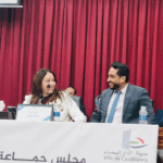 رجل وامرأة يتحدثان أمام ستارة حمراء.