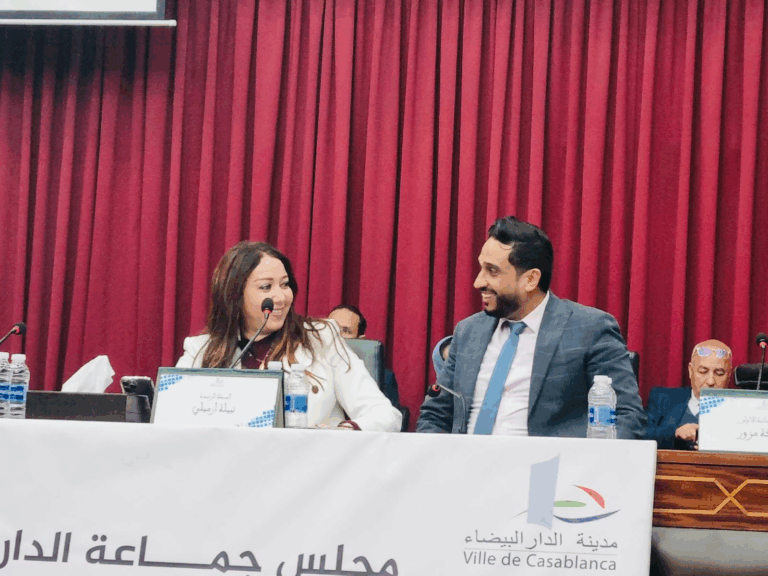 رجل وامرأة يتحدثان أمام ستارة حمراء.