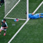 لاعب كرة قدم مكسيكي يسقط على الأرض وحارس جنوب إفريقيا ينظر.