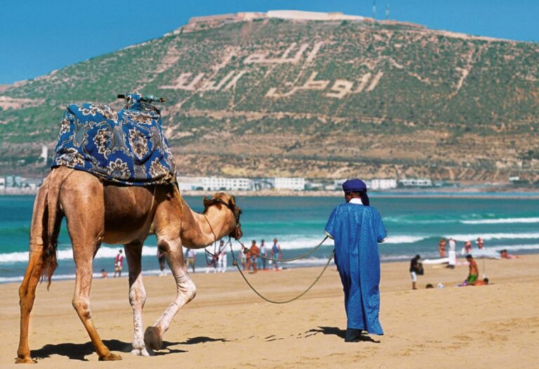 شخص يرتدي زيا تقليديا يركب جملا في الصحراء