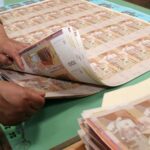 شخص يحمل ورقة نقدية من فئة 100 درهم ويطويها