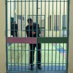 ضابط شرطة يقف أمام قضبان زنزانة.