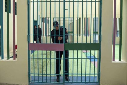 ضابط شرطة يقف أمام قضبان زنزانة.