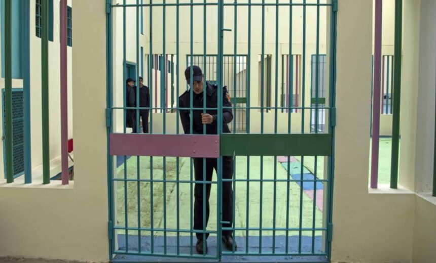 ضابط شرطة يقف أمام قضبان زنزانة.
