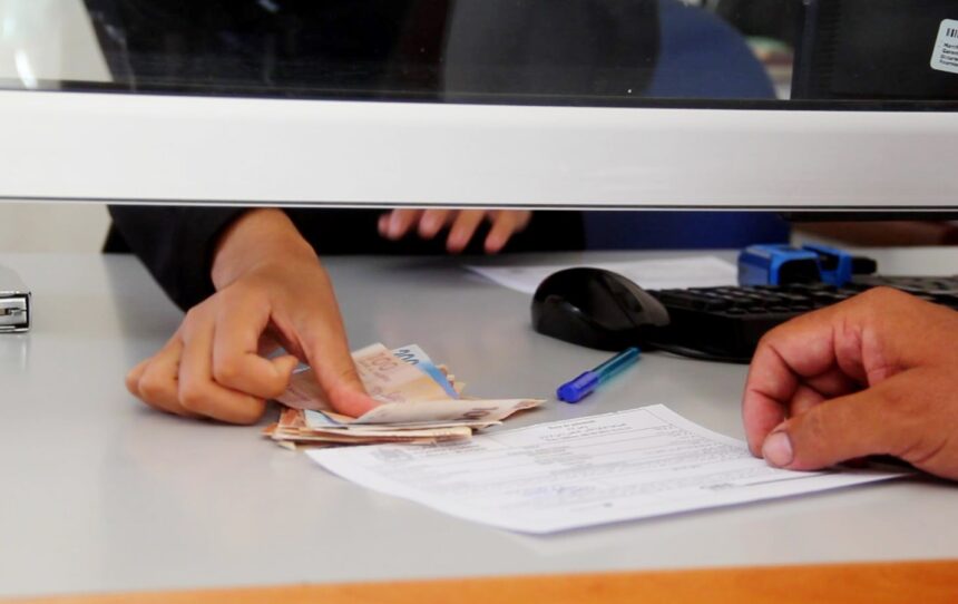 أيدٍ تتكدس فوق رزمة من الأوراق المالية.