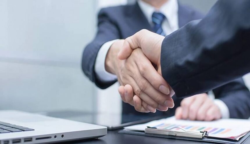 شخصان يتصافحان فوق طاولة عمل